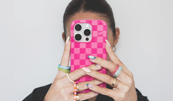 Person holding a pink checkered phone case with a white background - photographed in New Zealand
